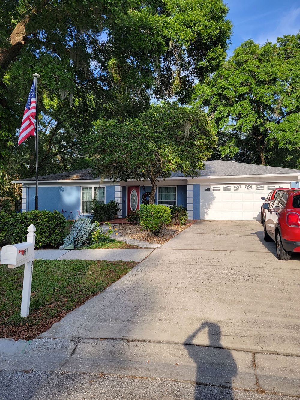 A blue house with a red car parked in front of it